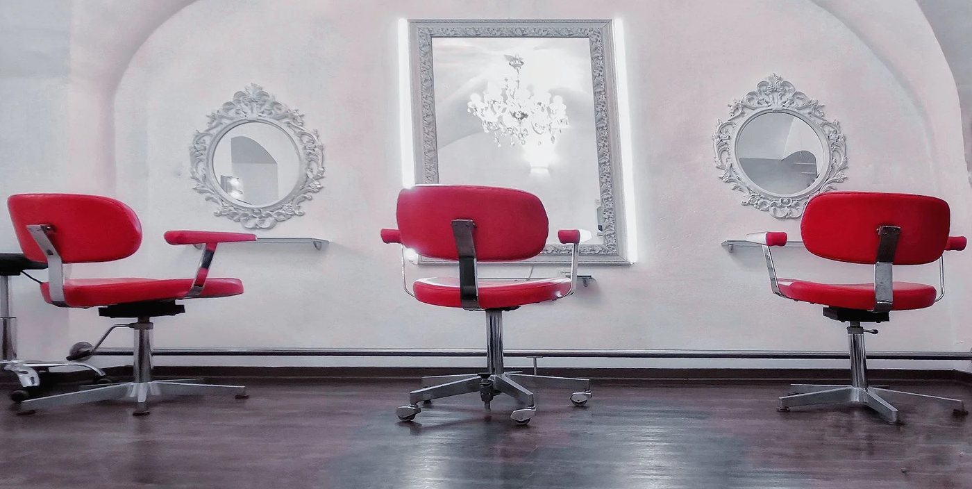Behandlungsplätze mit roten Friseurstühlen und barocken Spiegeln